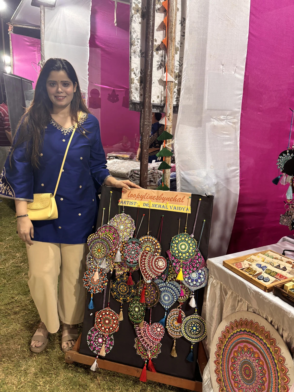 Nehal standing beside a display of colourful hanging mandala ornaments