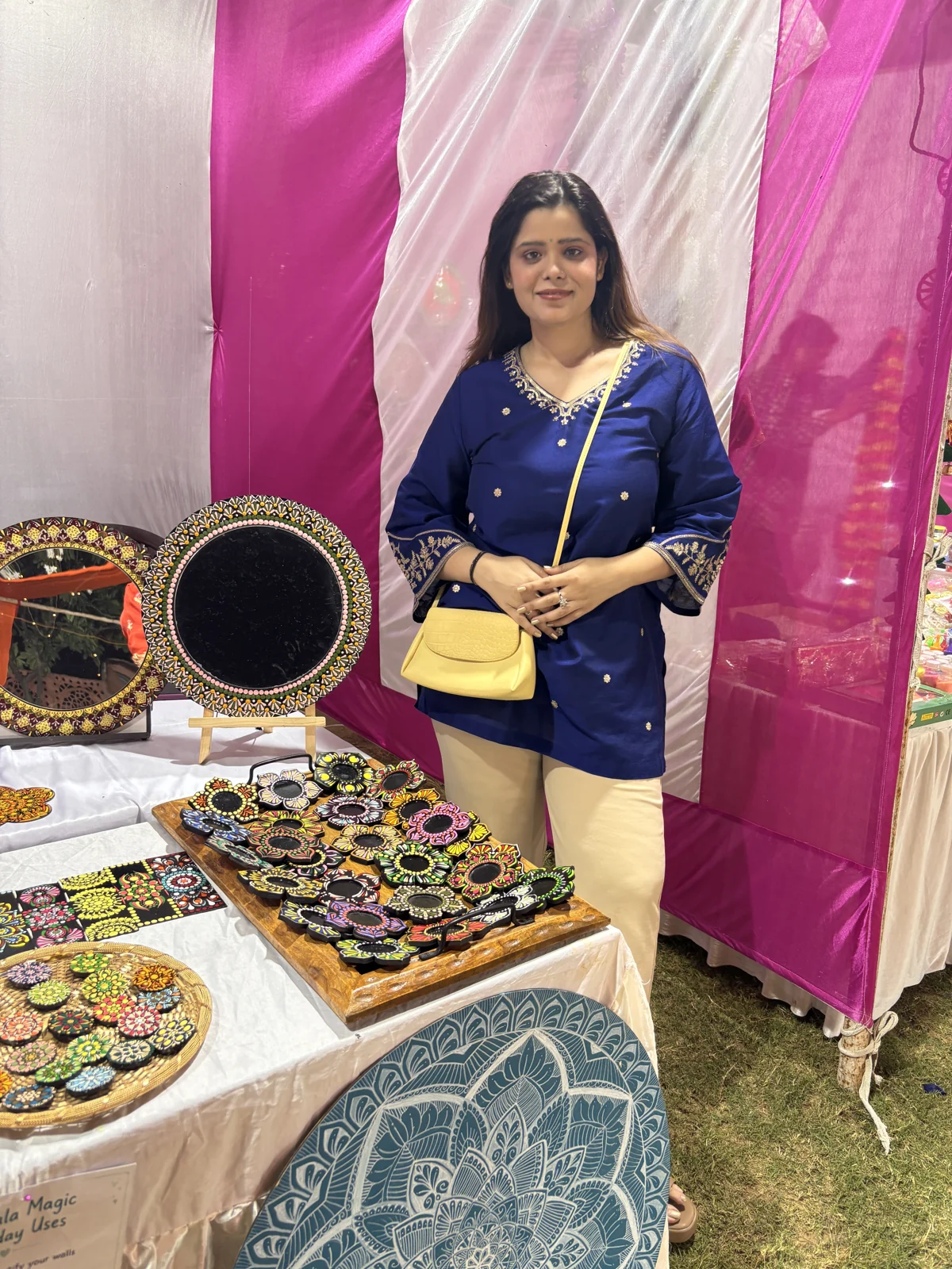 Nehal smiling beside her exhibition table, surrounded by her handmade artwork